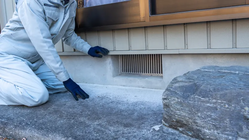 Inspector checking the base of an exterior wall